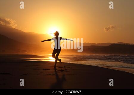 Frau in Yoga-Pose bei Sonnenuntergang am Strand in Kreta, Griechenland, Rückansicht Stockfoto