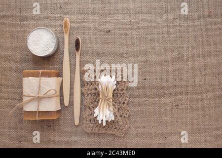 Set von natürlichen Bad-Tools, nachhaltige Lifestyle-Konzept. Holzzahnbürsten, Bambusstäbchen, Bio-Seife, Zahnpulver, Jute Waschlappen auf Stoff Stockfoto