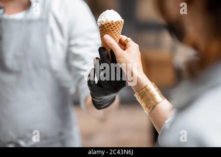 Verkauf von Eis in einem Waffelkegel für einen Kunden, Nahaufnahme Stockfoto
