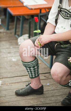 Mann in traditioneller bayerischer Kleidung hält eine Rose Stockfoto