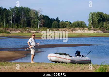 Der Fischer mit dem Motorboot am Flussufer Stockfoto