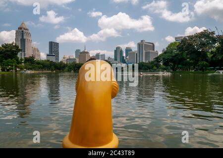 Bootsfahrt auf einem See im Lumphini Park in Bangkok, Thailand, mit den Wolkenkratzern der Rama IV Road im Hintergrund Stockfoto