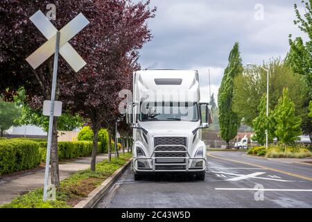 Big Rig Langstrecke Industriefracht weißen Semi-Truck mit Kühlergrill Guard und Sattelanhänger warten auf kommerzielle Fracht auf der nassen Straße geparkt wi Stockfoto