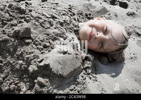 Mädchen im Sand begraben Stockfoto