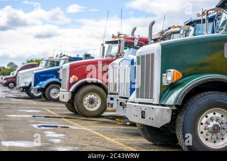 Verschiedene Marken, Modelle und Farben große Rigs Kipper Industriefracht semi-Trucks Traktoren stehen in Reihe auf dem Lager Parkplatz warten auf ne Stockfoto