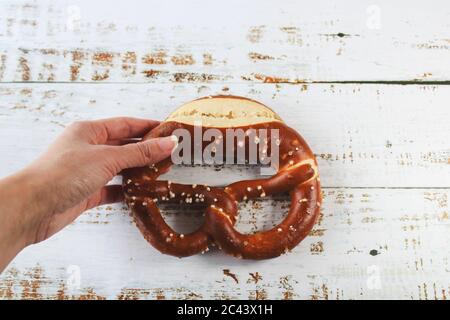 Frisch gebackene bayerische Brezel mit Salz auf rustikalem weißen Tisch. Perfekt für Oktoberfest. Nahaufnahme von hausgemachten Brezeln mit dunkler Kruste. Stockfoto