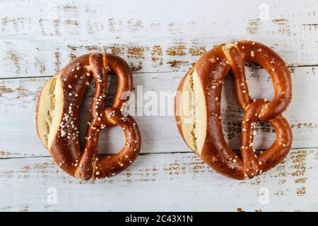 Frisch gebackene bayerische Brezel mit Salz auf rustikalem weißen Tisch. Perfekt für Oktoberfest. Nahaufnahme von hausgemachten Brezeln mit dunkler Kruste. Stockfoto