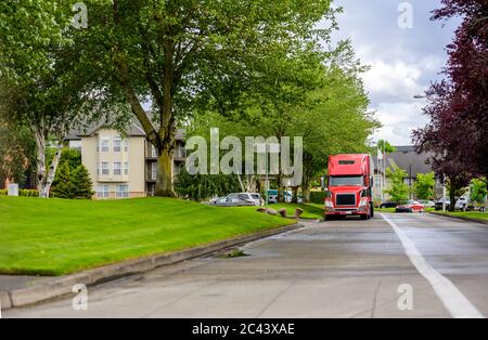 Big Rig Langstrecke Industriefracht roten Sattelschlepper mit Sattelauflieger auf der Stadtstraße in Wohngebiet auf den nächsten Zeitplan geparkt Stockfoto