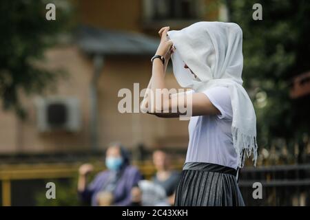 Snagov, Rumänien - 21. Juni 2020: Frau mit Schleier betet vor einer orthodoxen christlichen Kirche. Stockfoto