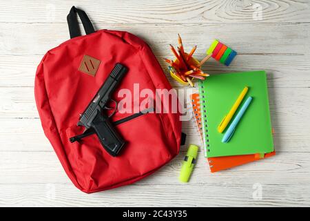 Schulzubehör und Pistole auf weißem Holztisch. Gewalt in der Schule Stockfoto