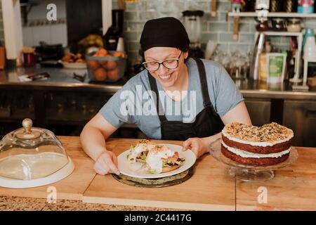 Porträt einer lächelnden Kellnerin, die in einem Café Essen serviert Stockfoto