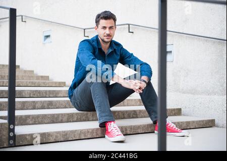 Junger Mann sitzt auf der Treppe Stockfoto