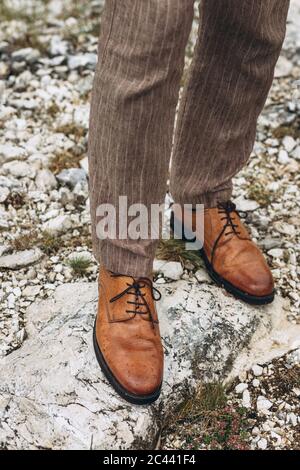 Nahaufnahme der Beine in braunen Schuhen mit Regentropfen. Herbstwetter. Wasserdichte Schuhe. Stockfoto