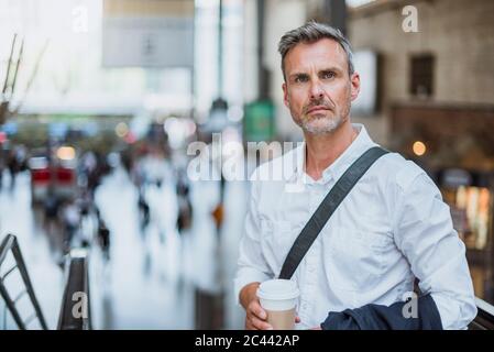 Selbstbewusster Geschäftsmann, der Kaffee hält, während er in der Stadt steht Stockfoto