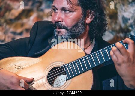 Nahaufnahme eines bärtigen, reifen Mannes, der Flamenco auf der Gitarre im Nachtclub spielt Stockfoto