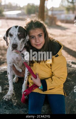 Nettes Mädchen umarmenden Hund während auf Stein sitzen Stockfoto