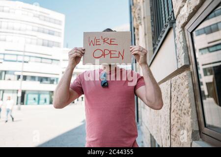 Ladenbesitzer hält Pappe mit Öffnungsansage in der Stadt Stockfoto