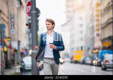 Portrait des jungen Geschäftsmannes mit Zeitung und Kaffee zu gehen auf der Straße Stockfoto