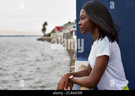 Profil der jungen Frau auf der Terrasse mit Blick auf das Meer Stockfoto