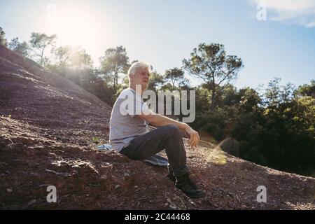 Älterer Mann, der während der Pause auf dem Boden sitzt Stockfoto