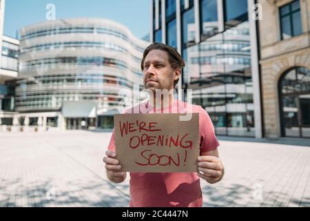 Ladenbesitzer hält Pappe mit Öffnungsansage in der Stadt Stockfoto