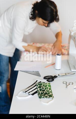 Hausgemachte Schutzmaske auf dem Tisch von Frau, die zu Hause arbeitet Stockfoto