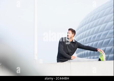 Junger Mann, der sich im Freien dehnt Stockfoto