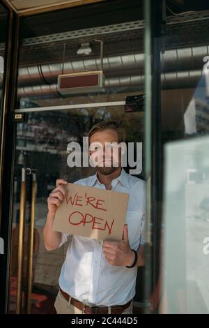 Ladenbesitzer hält Pappe mit Öffnungsansage in der Stadt Stockfoto