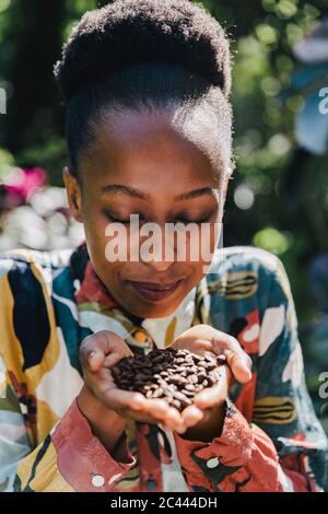 Porträt einer jungen Frau mit geschlossenen Augen riechend gerösteten Kaffeebohnen Stockfoto