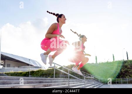 Junge aktive Frauen springen über Stufen gegen den Himmel Stockfoto