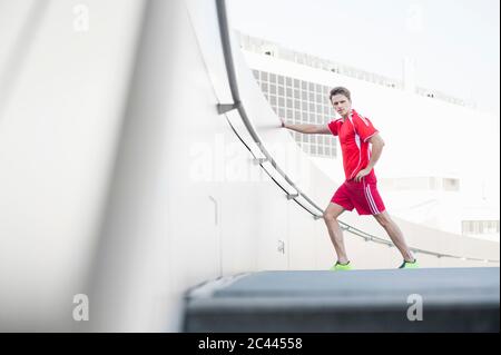 Mittelalter Mann, der sich durch Stützmauer auf der Straße in der Stadt streckt Stockfoto