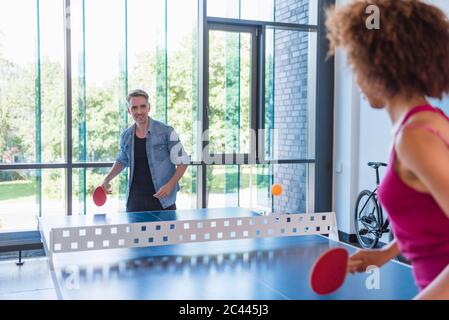 Junge Geschäftsleute, die Tischtennis im Loft-Büro spielen Stockfoto