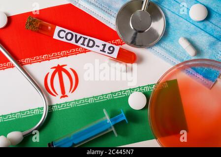 Coronavirus, das Konzept COVid-19. Draufsicht auf eine schützende Atemmaske, Stethoskop, Spritze, Pillen auf der Flagge des Iran. Ein neuer Ausbruch des Chi Stockfoto