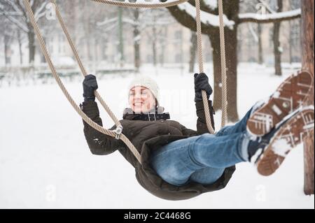 Porträt einer glücklichen Frau auf Schaukel im Winter Stockfoto