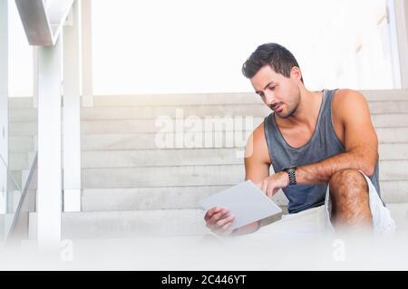 Portrait des jungen Mannes auf der Treppe mit Tablet Stockfoto