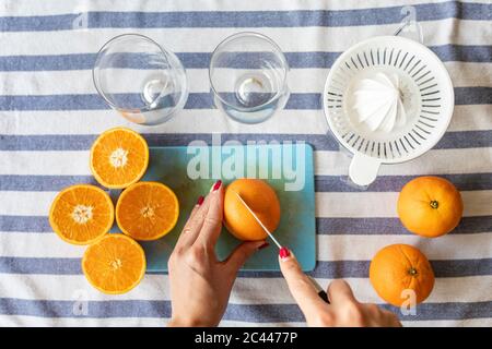 Frau schneiden frische Orangen für frisch gepressten Orangensaft Stockfoto