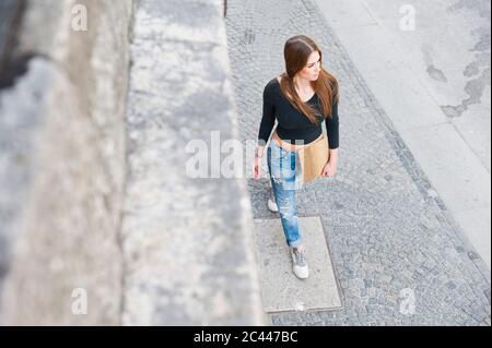 Modische Frau, die auf dem Bürgersteig in der Stadt läuft Stockfoto