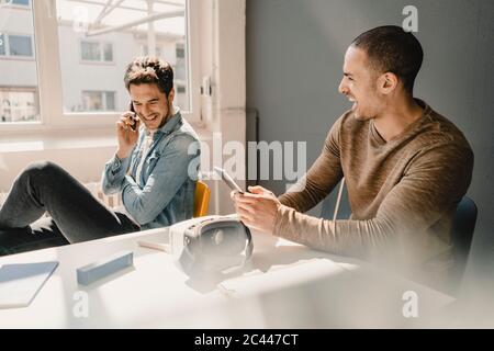 Junge Geschäftsleute arbeiten zusammen im Büro, telefonieren Stockfoto