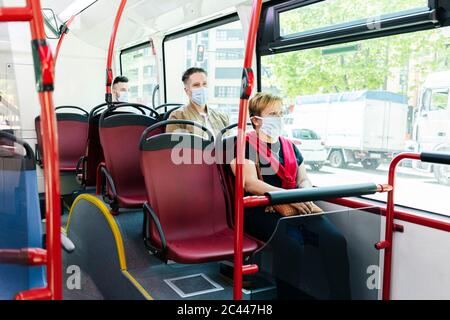 Passagiere mit Schutzmasken im öffentlichen Bus, Spanien Stockfoto