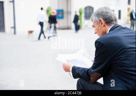 Senior Geschäftsmann liest Zeitung im Freien Stockfoto