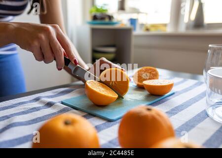 Frau schneiden frische Orangen für frisch gepressten Orangensaft Stockfoto