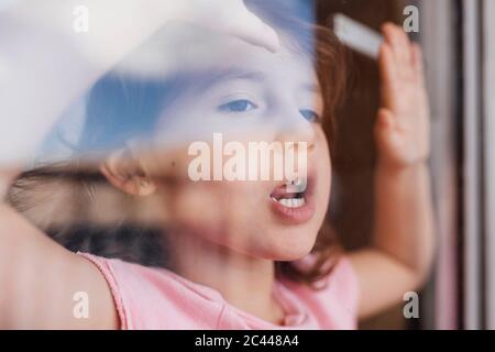 Portrait von kleinen Mädchen Blick aus Fenster Stockfoto