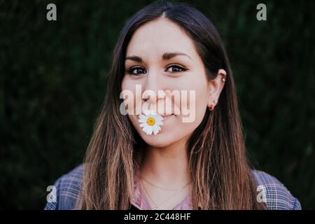 Porträt einer lächelnden Frau mit marguerite im Mund Stockfoto