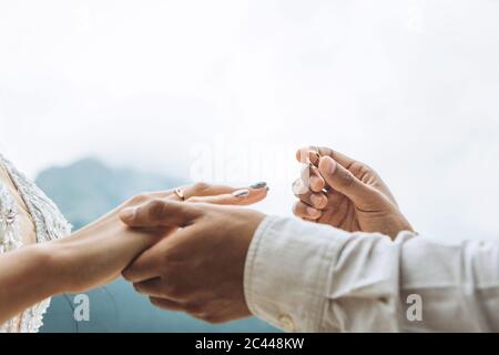 Nahaufnahme eines Bräutigams, der einen Ehering auf den Finger der Braut legt. Stockfoto