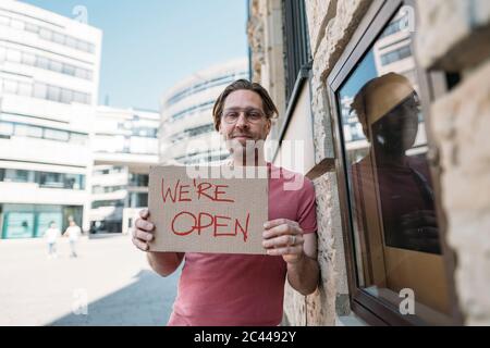 Ladenbesitzer hält Pappe mit Öffnungsansage in der Stadt Stockfoto