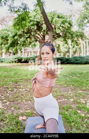 Frau mittleren Erwachsenen Yoga auf Matte im Park üben Stockfoto