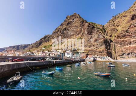 Portugal, Madeira Island, Paul do Mar, Fischerboote liegen im Hafen, Berg und Stadt im Hintergrund Stockfoto