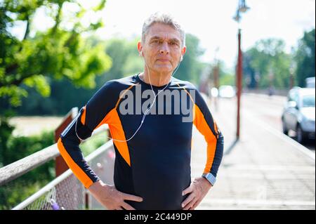 Porträt eines selbstbewussten älteren Mannes in Sportkleidung, der an sonnigen Tagen mit Händen auf der Hüfte steht Stockfoto