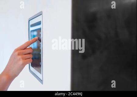 Hand der Frau mit digitalen Blitzsteuerung an der Wand zu Hause montiert Stockfoto