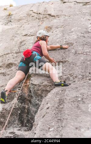 Junge Frau klettert auf den Felsen Stockfoto